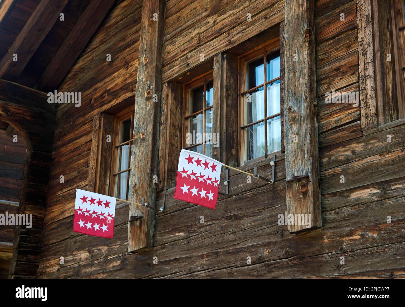 Zwei Flaggen des Kantons Wallis im Fenster eines Schweizer Chalets, Blatten bei Naters, Wallis, Schweiz Stockfoto