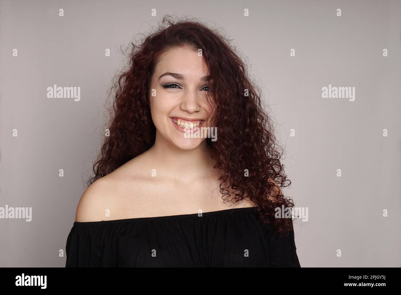 Glückliches Teenager-Mädchen mit langen Locken und einem großen Grinsen Stockfoto