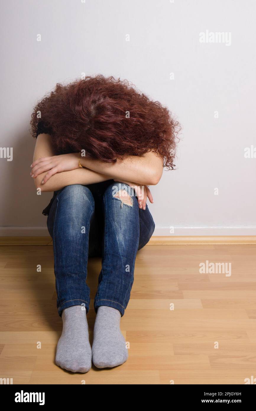 Traurig, deprimiert junge Frau, die ihr Gesicht sitzen auf dem Boden ausblenden Stockfoto