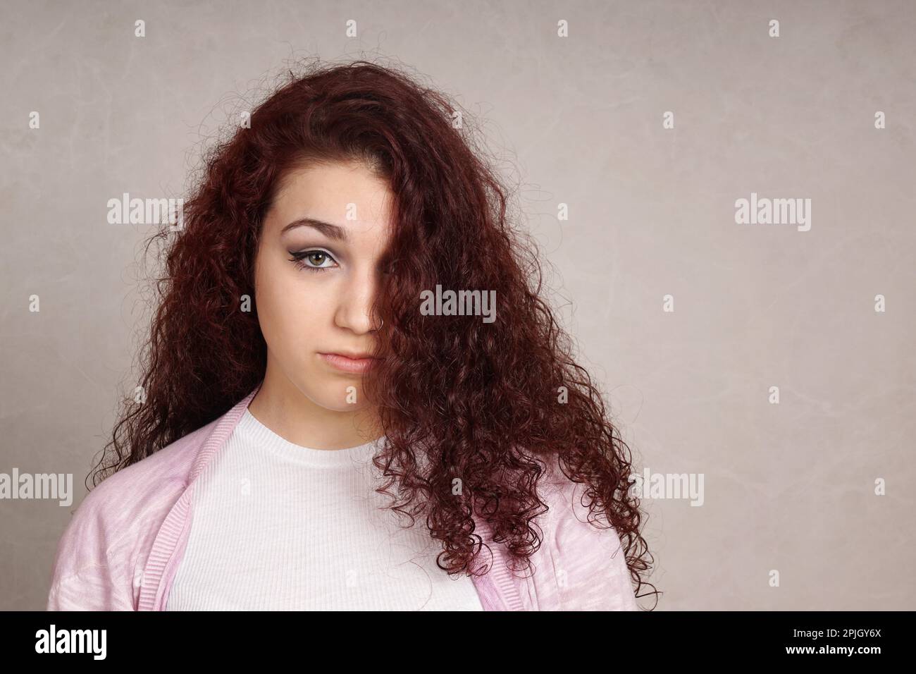 Traurige Teenager suchen gedrückt versteckt sich die Hälfte der ihr Gesicht hinter den langen, lockigen Haar Stockfoto