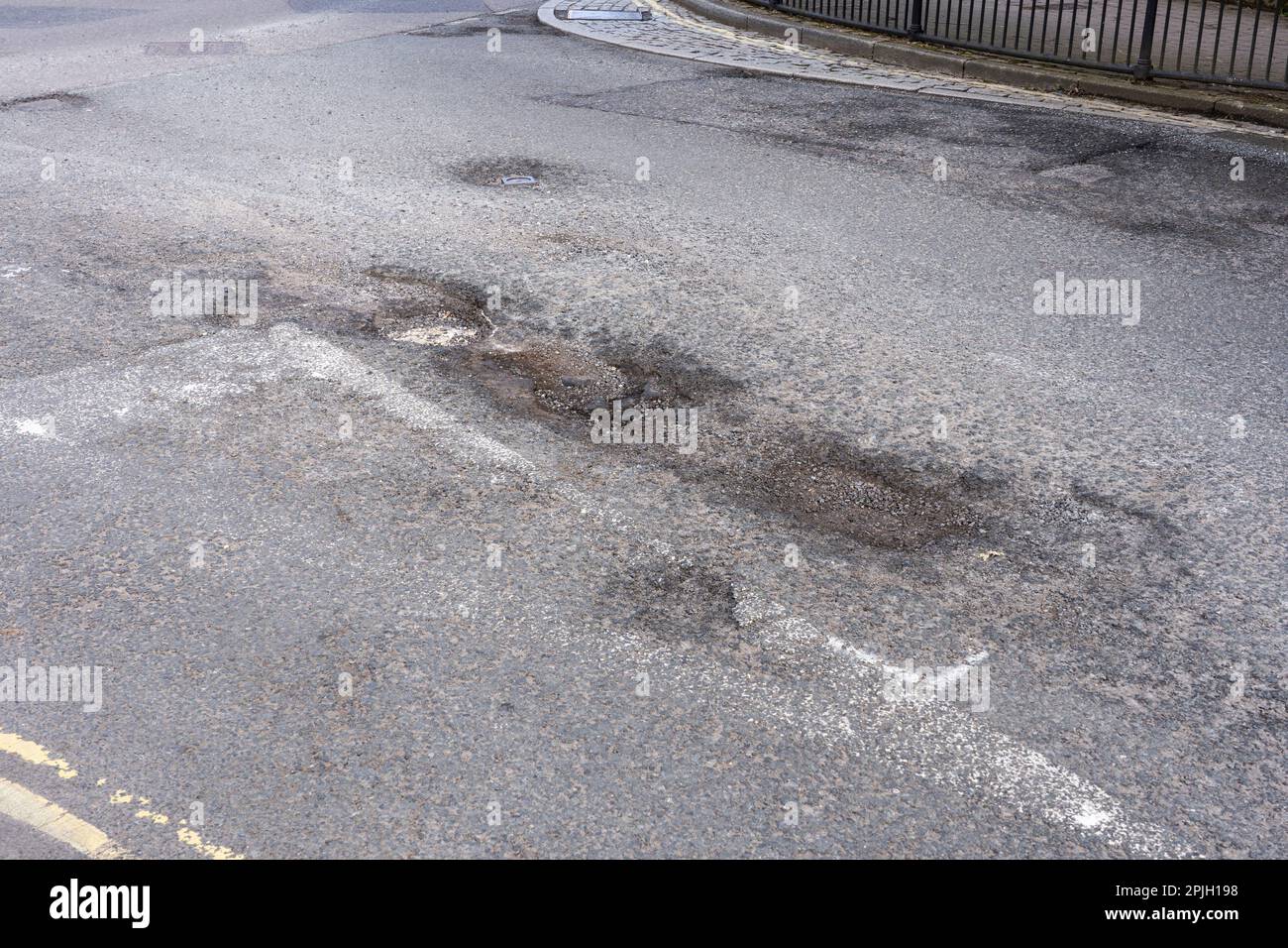 Große Schlaglöcher an einer Kreuzung auf der Winchester Road. Basingstoke, Großbritannien. Die Finanzierungslücke bei der örtlichen Straßeninstandhaltung ist seit Jahren am größten. März 2023 Stockfoto
