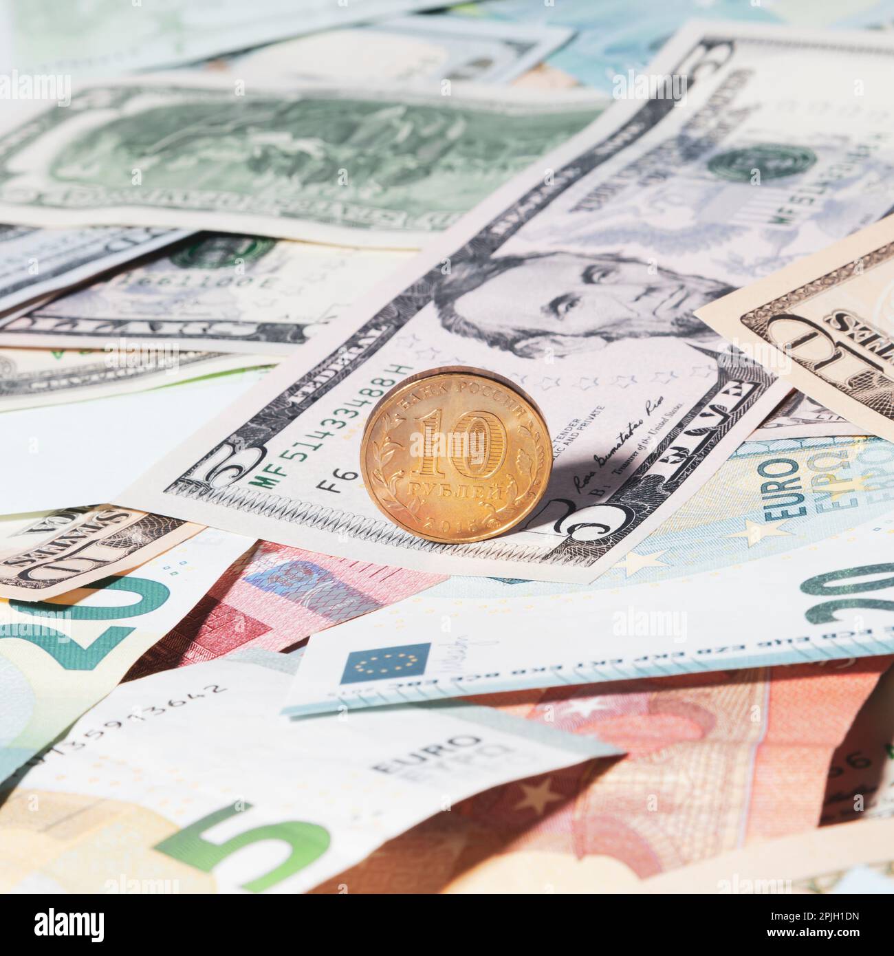 Eine goldfarbene Münze mit einer Stückelung von 10 russischen Rubel liegt auf US- und europäischen Papiergeld verschiedener Stückelungen - USD, EUR Ansicht f Stockfoto