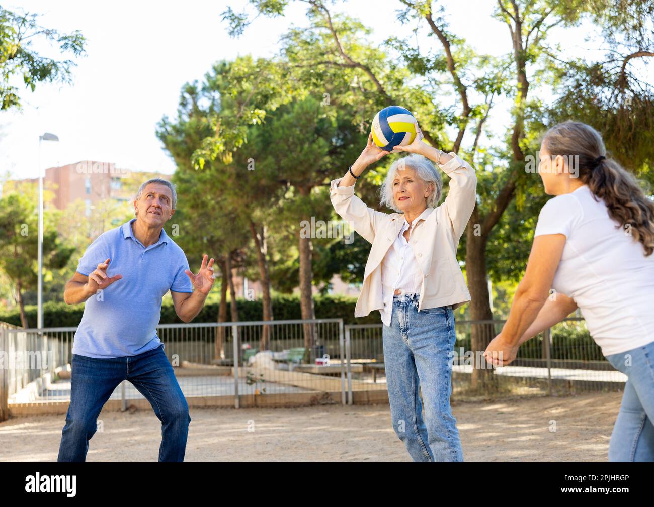 Alte multinationale Menschen spielen Volleyball-Aktivität auf einem Sommerspielplatz für Sport im Frühling draußen Stockfoto