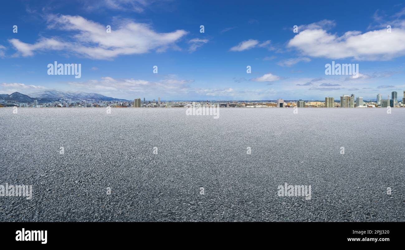 Leerer Asphaltboden mit weit entferntem Stadtbild-Hintergrund Stockfoto