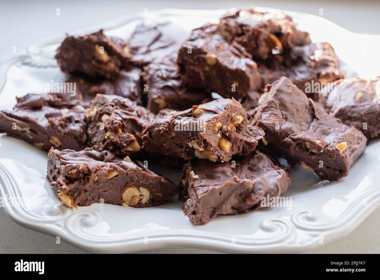 Hausgemachte Erdnussschokolade-Toffee-Quadrate auf weißem Teller, weißer Hintergrund. USA. Stockfoto