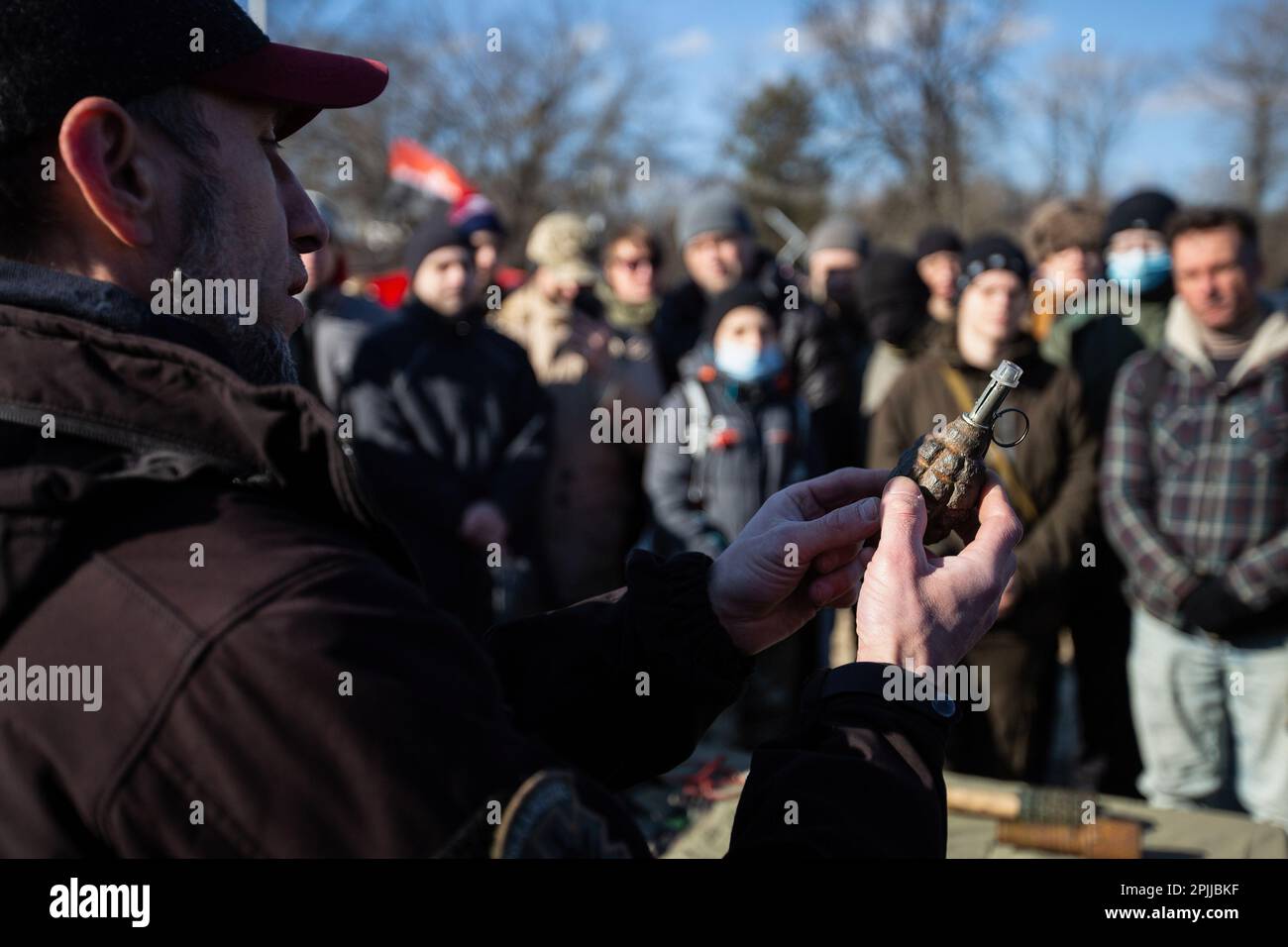 Ein territorialer Verteidigungskämpfer demonstriert bei einer Übung für Zivilisten eine Handgranate, die an einem städtischen Strand in Kiew trainiert wird, während eine russische Invasion der Ukraine droht. Stockfoto