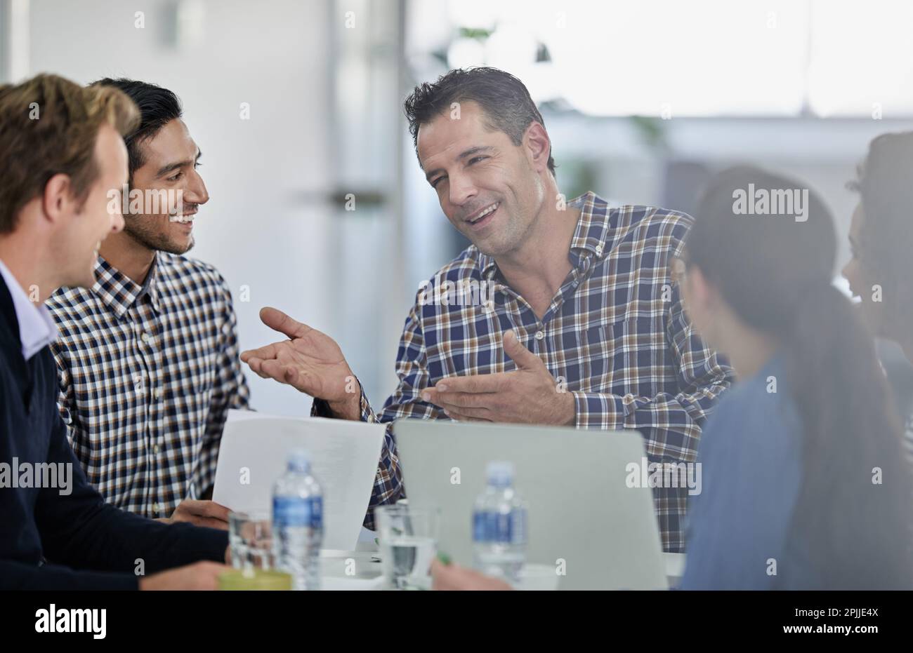 Er ist ein großartiger Kommunikator. Gruppe von Kollegen, die an einem Besprechungstisch sitzen und eine Diskussion führen. Stockfoto
