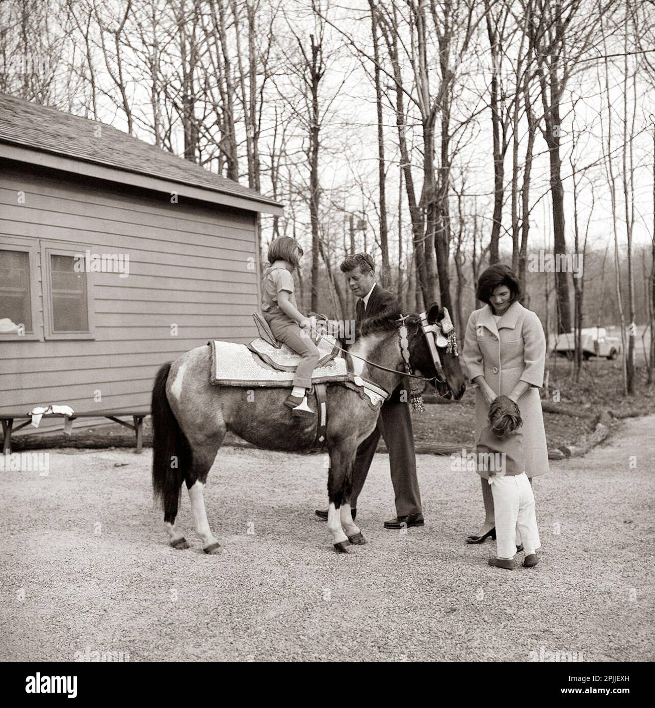 KN-C27671 Wochenende am 31. März 1963 im Camp David. Präsident Kennedy und Mrs. Kennedy mit ihren Kindern Caroline und John Jr. im Camp David in Maryland. Caroline sitzt auf "Macaroni". Der Sattel auf Macaroni war ein Geschenk von König Hassan II. Von Morroco. Bitte schreiben Sie Robert Knudsen. Fotos Vom Weißen Haus. John F. Kennedy Presidential Library and Museum, Boston“ Stockfoto