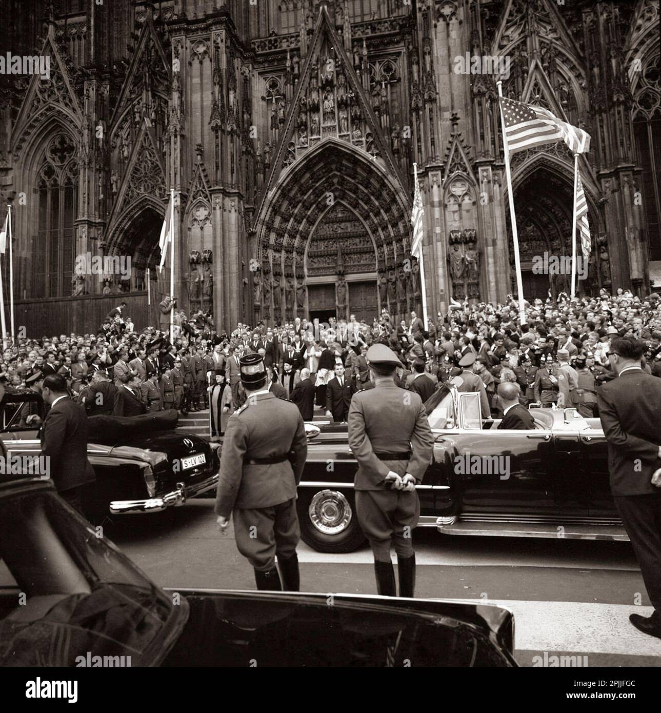 KN-C29239 Am 23. Juni 1963 versammelt sich eine große Menschenmenge, während Präsident John F. Kennedy den Kölner Dom während seiner Reise nach Köln verlässt. Auf dem Foto sind Präsident Kennedy, Zuschauer, Geistliche und Autokolonne zu sehen. Rathous Blorplatz, Köln, Deutschland. Bitte schreiben Sie Robert Knudsen. Fotos Vom Weißen Haus. John F. Kennedy Presidential Library and Museum, Boston“ Stockfoto