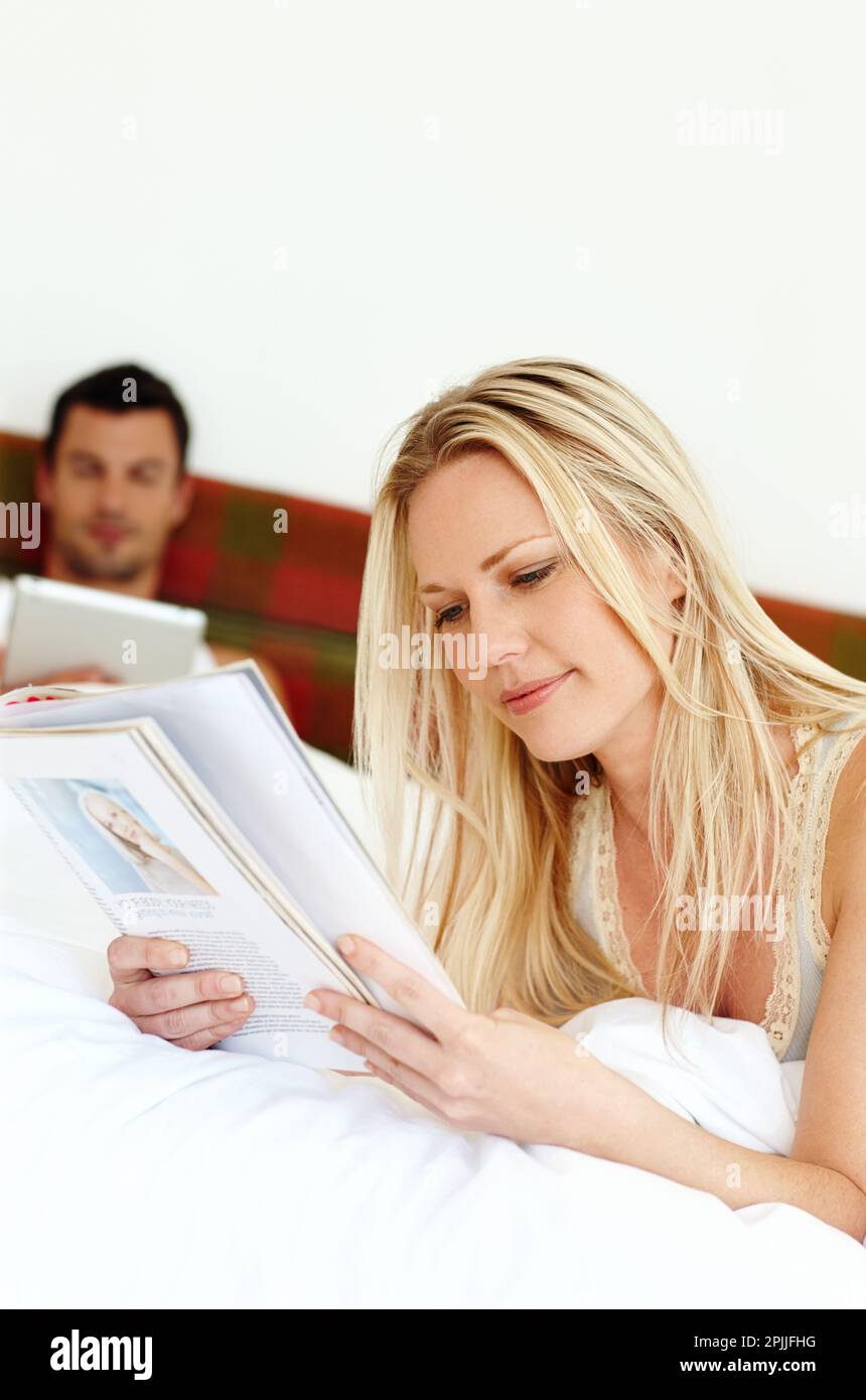 Sonntagmorgen Glückseligkeit. Ein glückliches, entspanntes Paar, das morgens zusammen im Bett las. Stockfoto