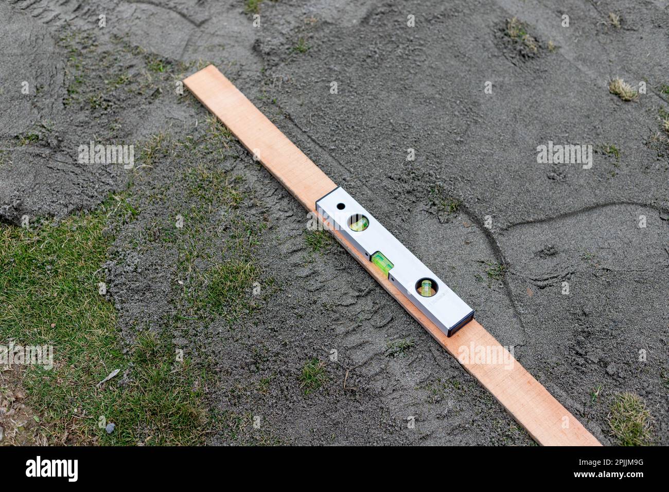 Vorbereitung und Nivellierung des Rasens mit Sand mit einer Wasserwaage Stockfoto