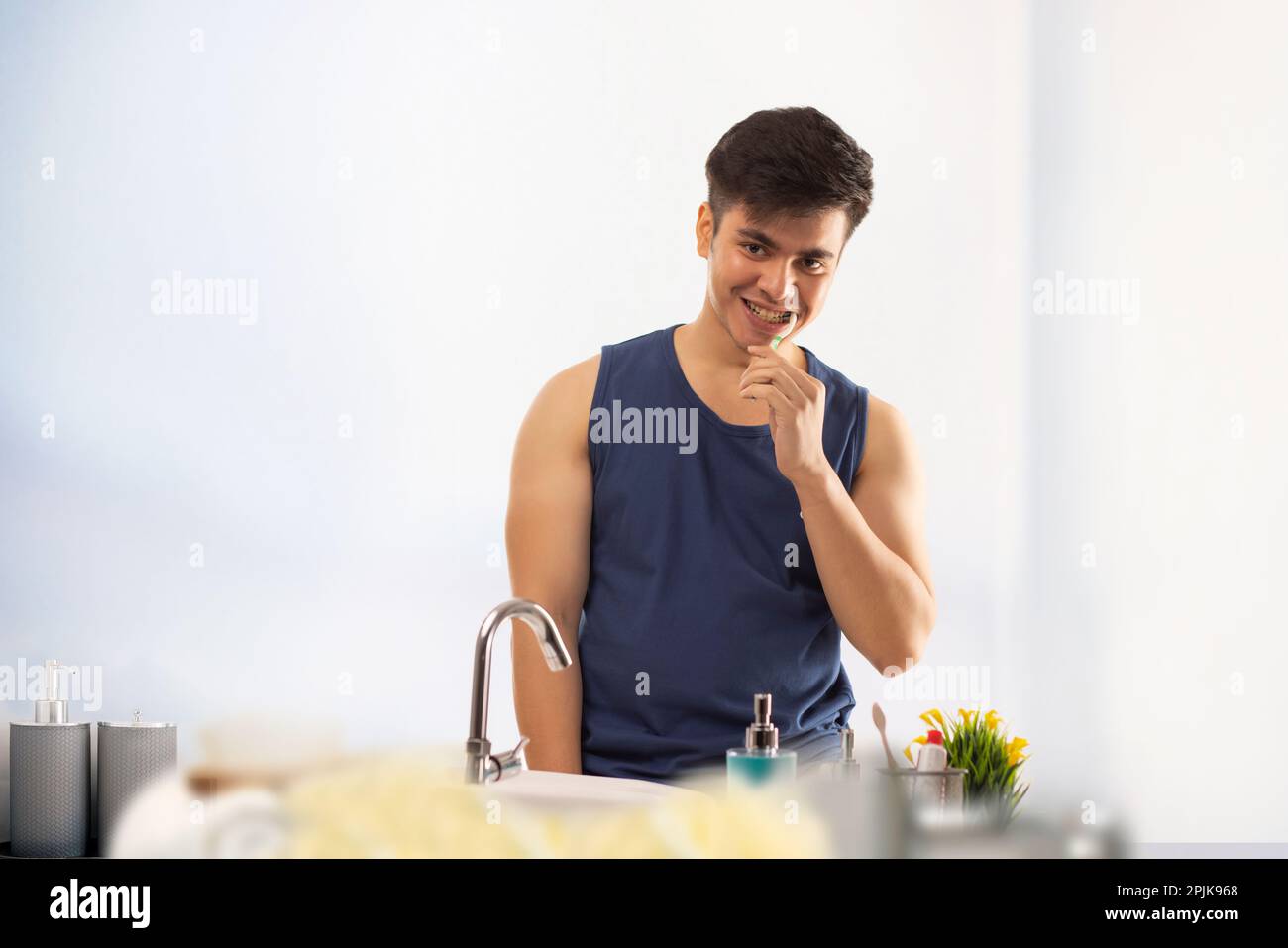 Ein junger Mann putzt sich die Zähne vor dem Badezimmerspiegel Stockfoto