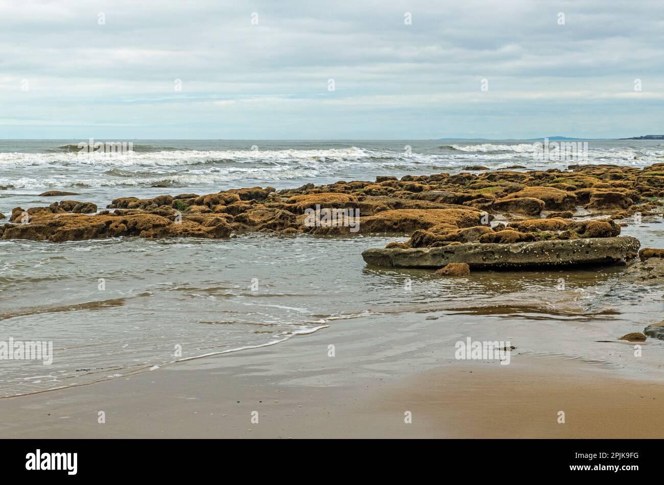Dunraven Bay, mit Blick auf das Meer, mit Flut an der Kurve und viel nassem Sand und Felsen mit Blick auf den Bristol Channel. Stockfoto