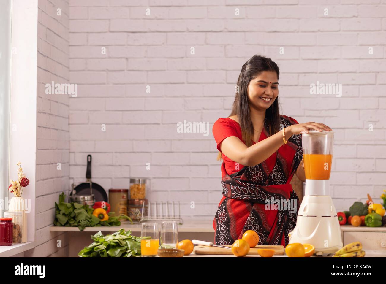 Frau macht Orangensaft in Küche Stockfoto