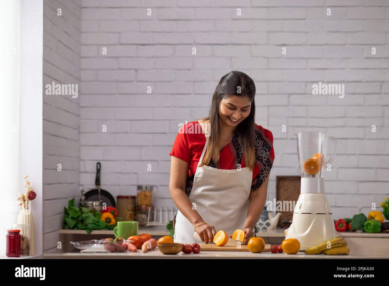 Porträt einer fröhlichen Frau, die frisches Obst in der Küche hackt Stockfoto