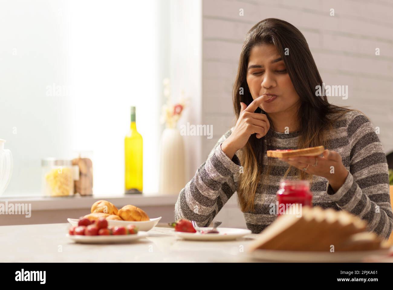 Eine Frau, die ihr Frühstück in der Küche genießt Stockfoto