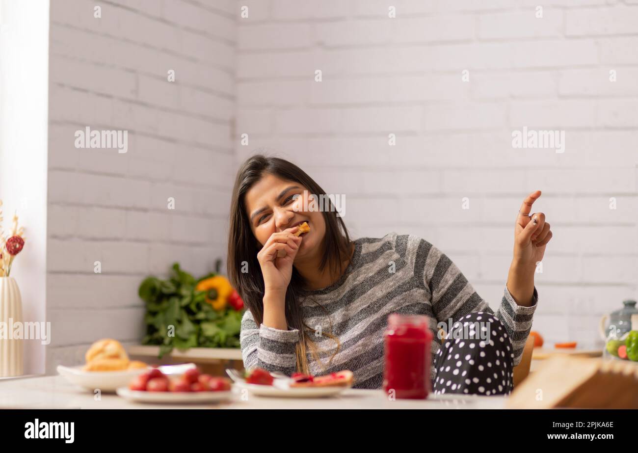 Frau, die zu Hause beim Frühstück Croissants isst Stockfoto