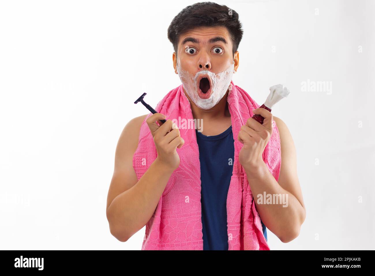 Porträt eines überraschten Jungen, der beim Rasieren im Badezimmer in die Kamera schaut Stockfoto