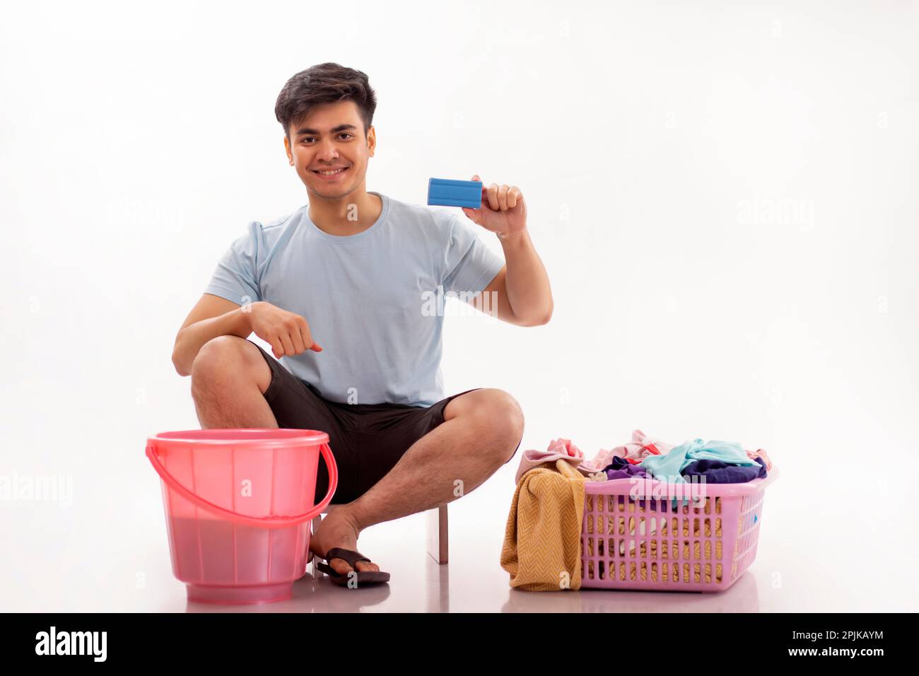 Ein glücklicher junger Mann, der Wäscheseifenriegel zeigt, der in der Hand hält Stockfoto