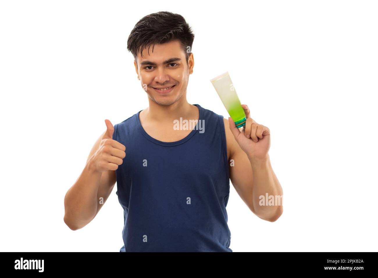 Fröhlicher junger Mann, der auf die Gesichtswäsche zeigt, die er in der Hand hält und Daumen nach oben zeigt Stockfoto