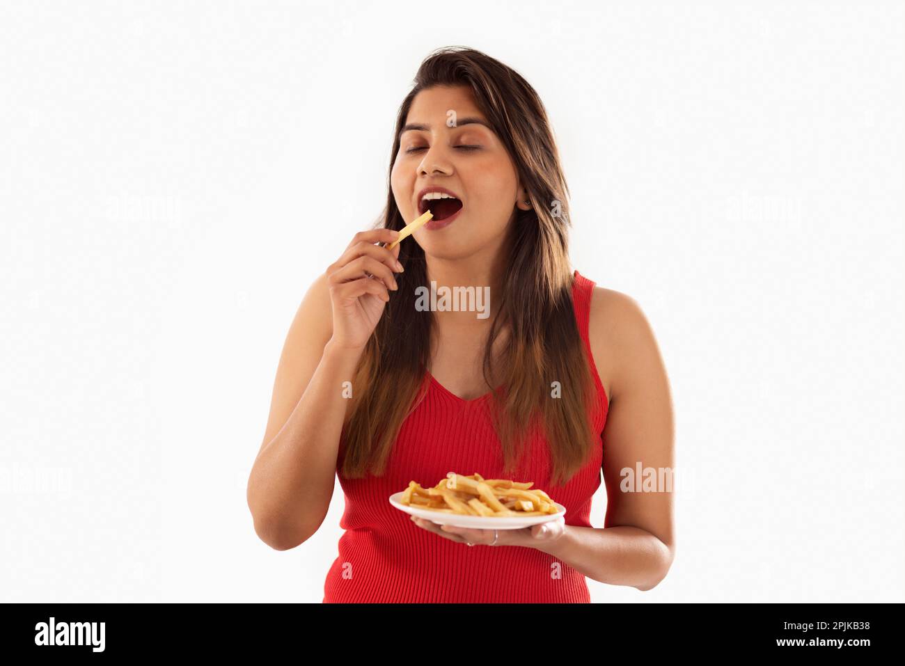 Eine Frau, die pommes Frites vor weißem Hintergrund isst Stockfoto