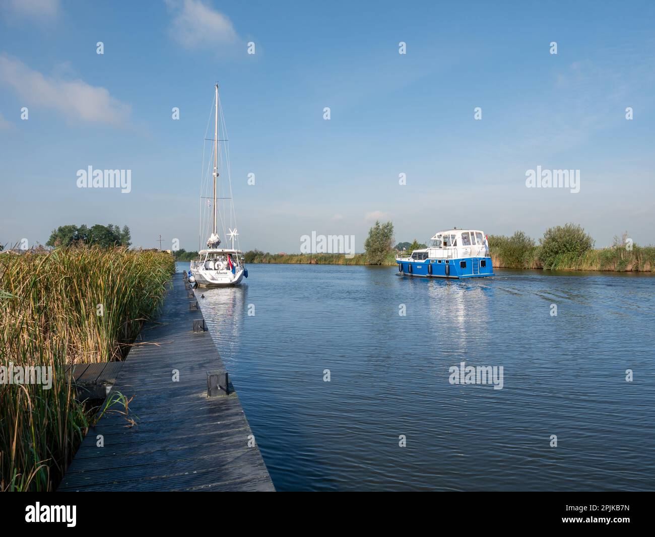 Segelboot und Motorboot auf dem Janesloot River im Seebezirk Friesland, Niederlande Stockfoto
