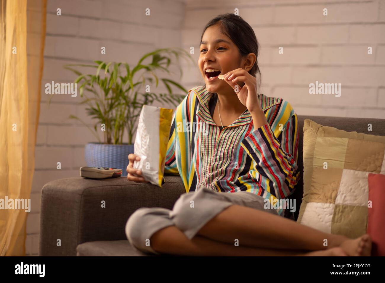 Porträt eines aufgeregten Mädchens, das im Wohnzimmer fernsieht Stockfoto