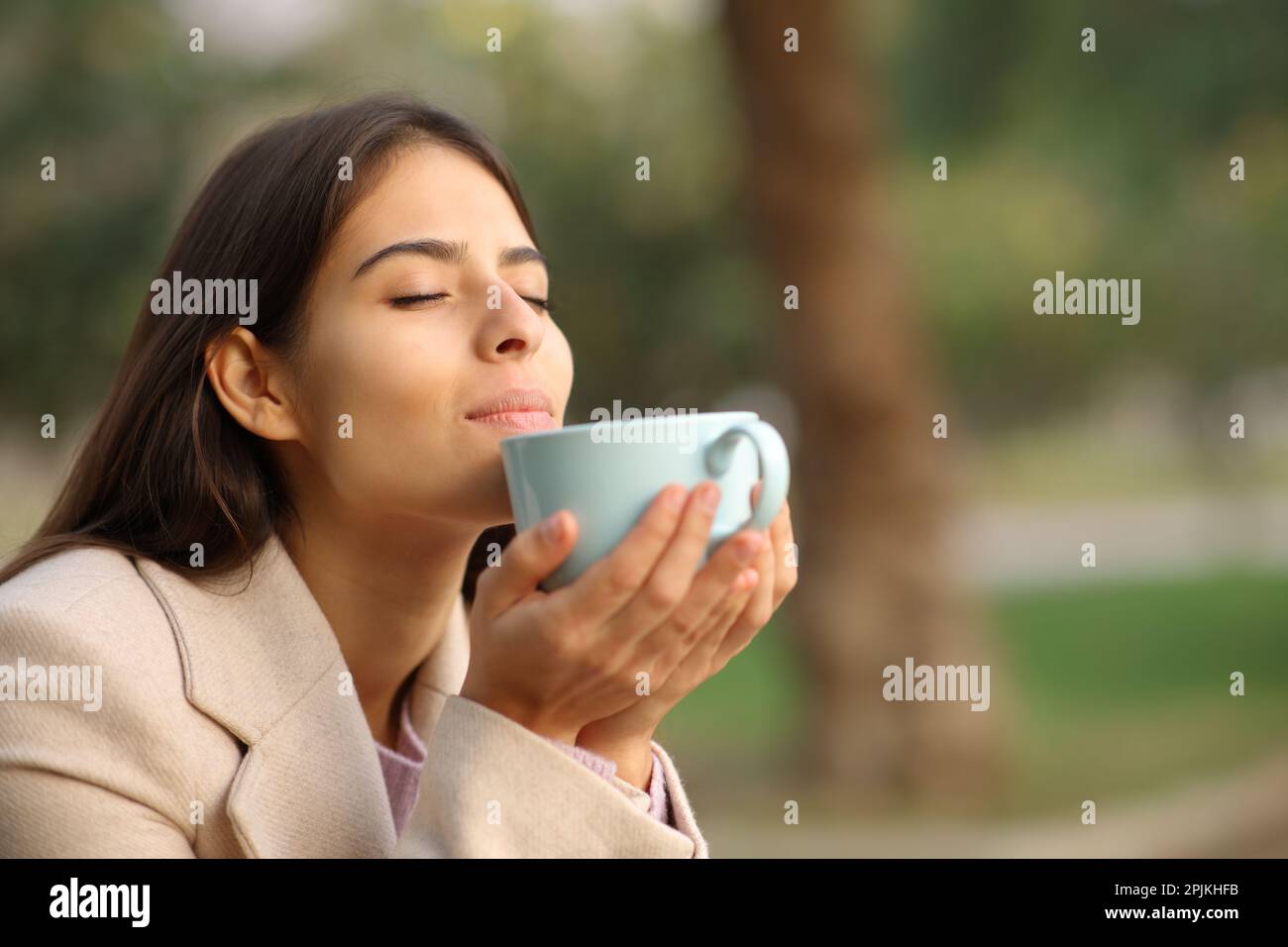Eine Frau im Winter, die in einem Park nach Kaffeearoma riecht Stockfoto