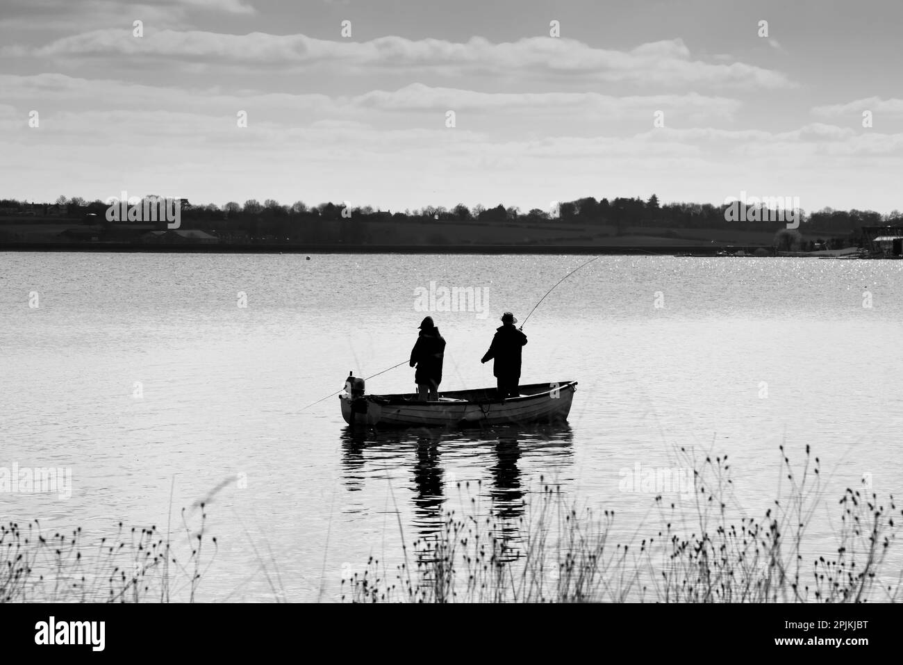 Zwei Männer fischen von einem kleinen Boot aus auf dem ruhigen Wasser eines Sees als entspannendes Hobby Stockfoto