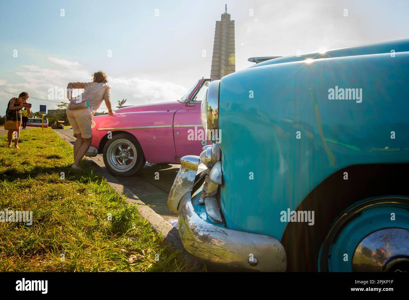 Kuba. Havanna. Eine Frau posiert mit klassischen Autos. Stockfoto