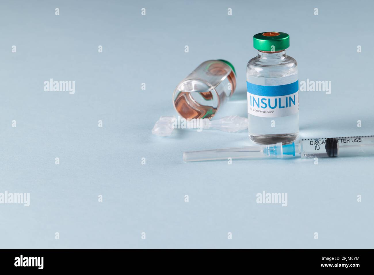 Durchstechflaschen mit Insulin mit Kapseln und Spritze auf blauem Hintergrund mit Kopierbereich Stockfoto