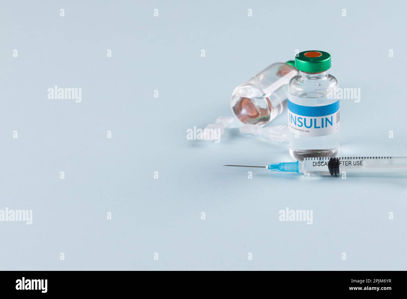 Durchstechflaschen mit Insulin mit Kapseln und Spritze auf blauem Hintergrund mit Kopierbereich Stockfoto