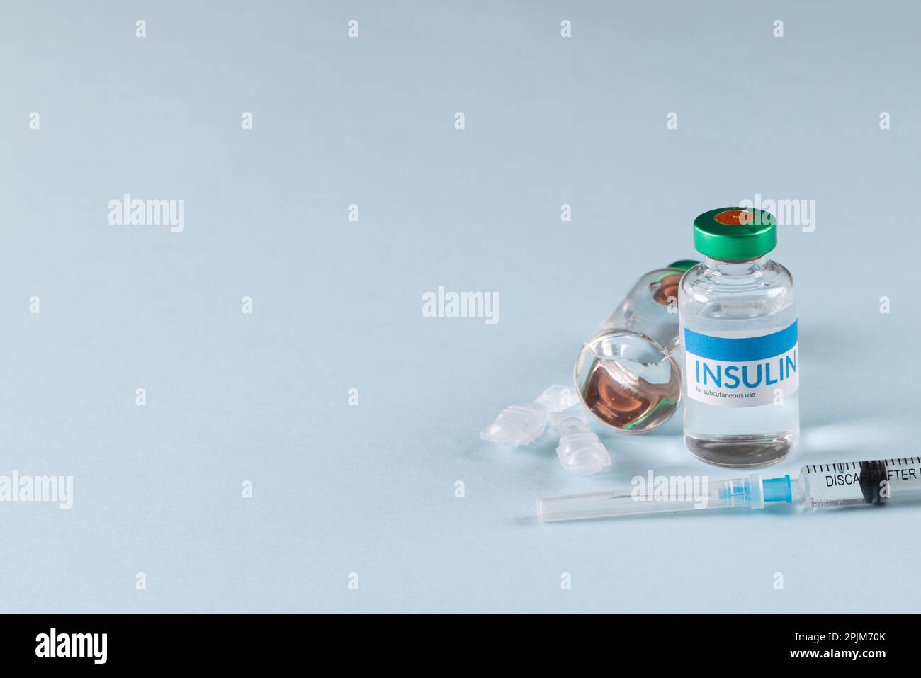 Durchstechflaschen mit Insulin mit Kapseln und Spritze auf blauem Hintergrund mit Kopierbereich Stockfoto