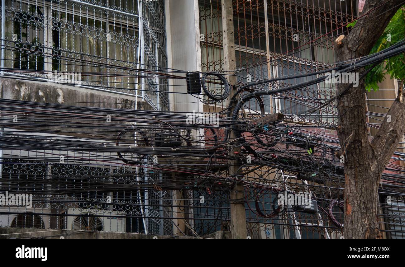 Unordentliche Strom- und Internetkabel an einem Pol, Chaos an Kabeln und Drähten an einem Pol in Thailand Stockfoto