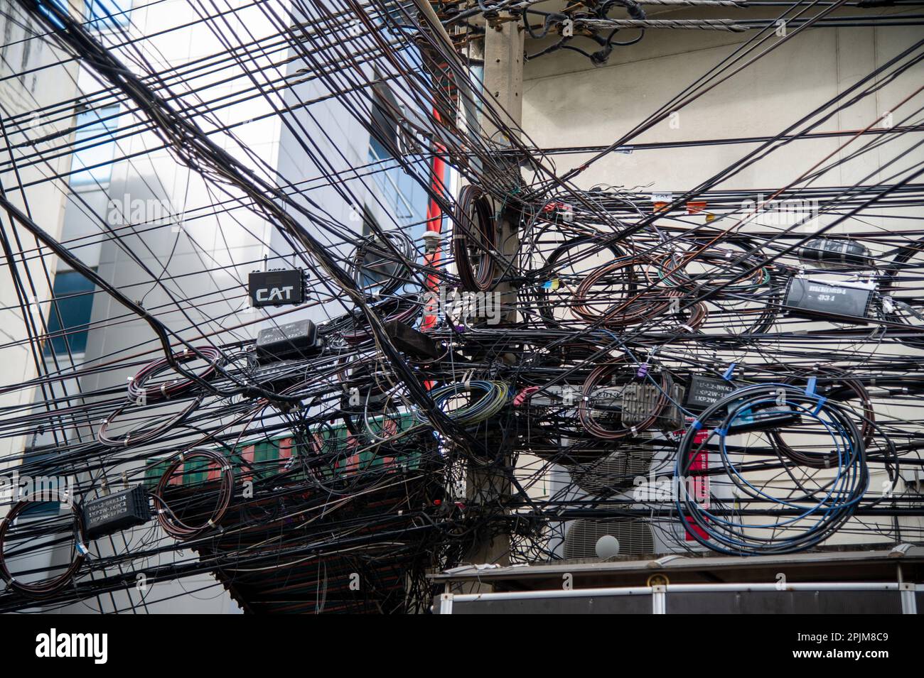 Unordentliche Strom- und Internetkabel an einem Pol, Chaos an Kabeln und Drähten an einem Pol in Thailand Stockfoto