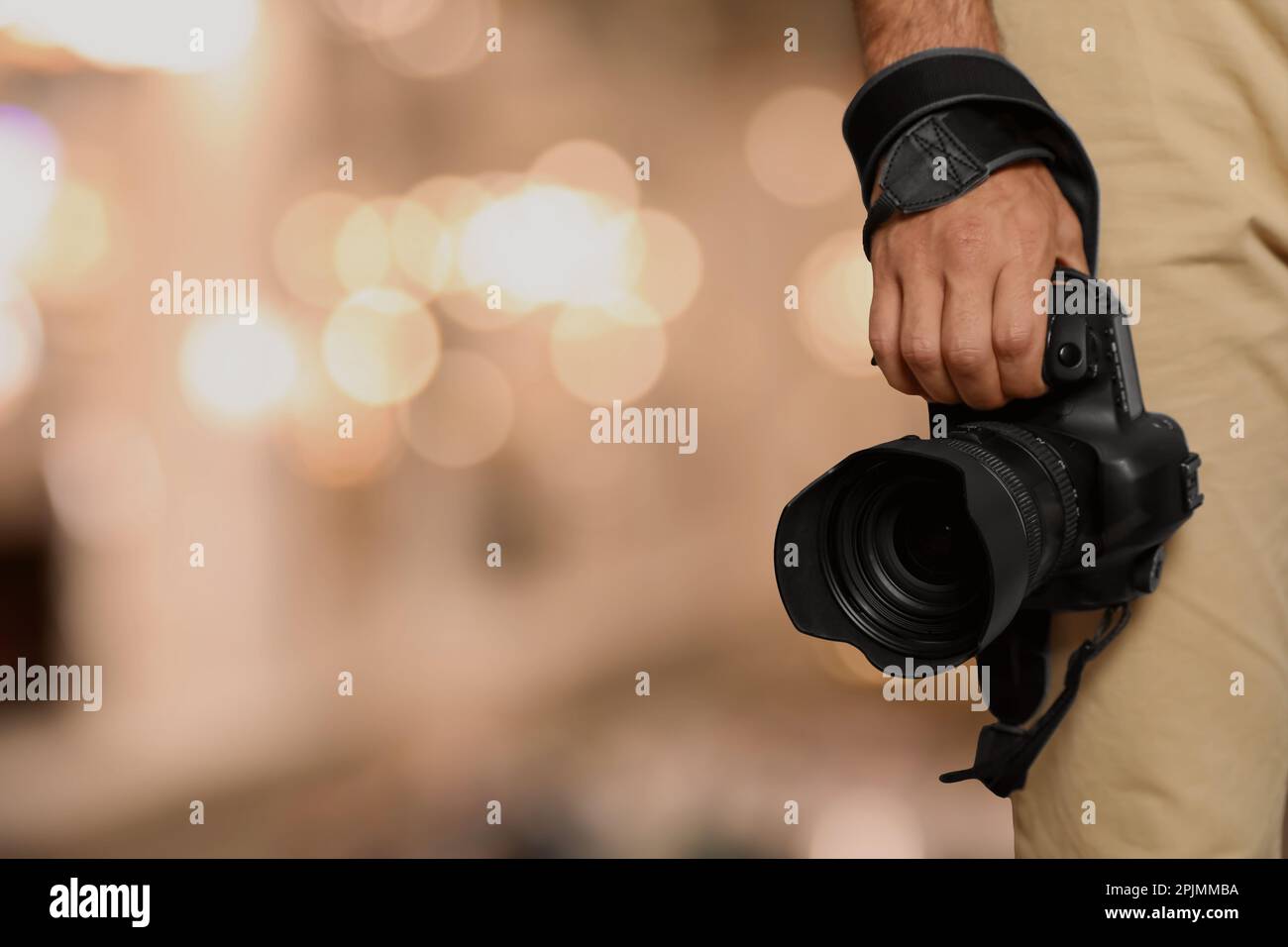 Professioneller Fotograf mit moderner Kamera und verschwommenem Hintergrund, Platz für Text Stockfoto