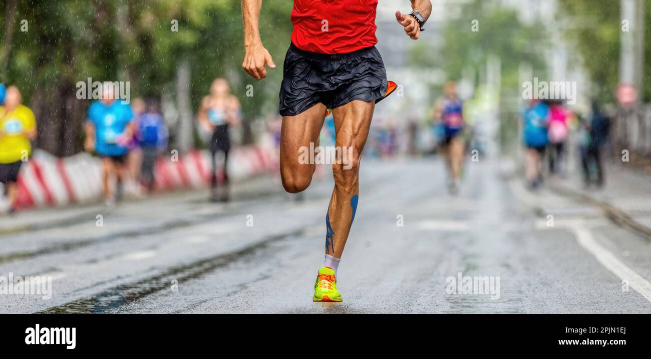 Männlicher Läufer, der ein Marathon-Stadtrennen läuft, Athlet, der nach Regen auf nassem Asphalt läuft, muskulöser Bein-Jogger Stockfoto