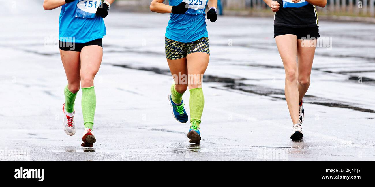 Gruppe Läuferinnen Athleten laufen Marathon, Vorderansicht Frauenbein Jogger in Kompressionssocken laufen nasse Straßen Stockfoto