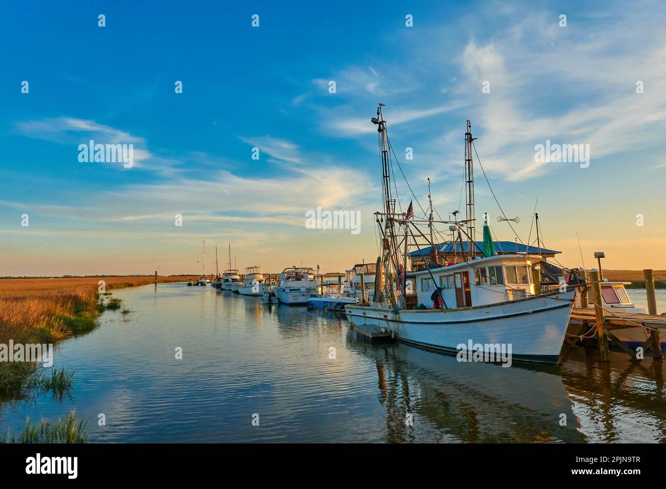 Sonnenuntergang mit Garnelenbooten entlang einer Anlegestelle auf Tybee Island, Georgia Stockfoto