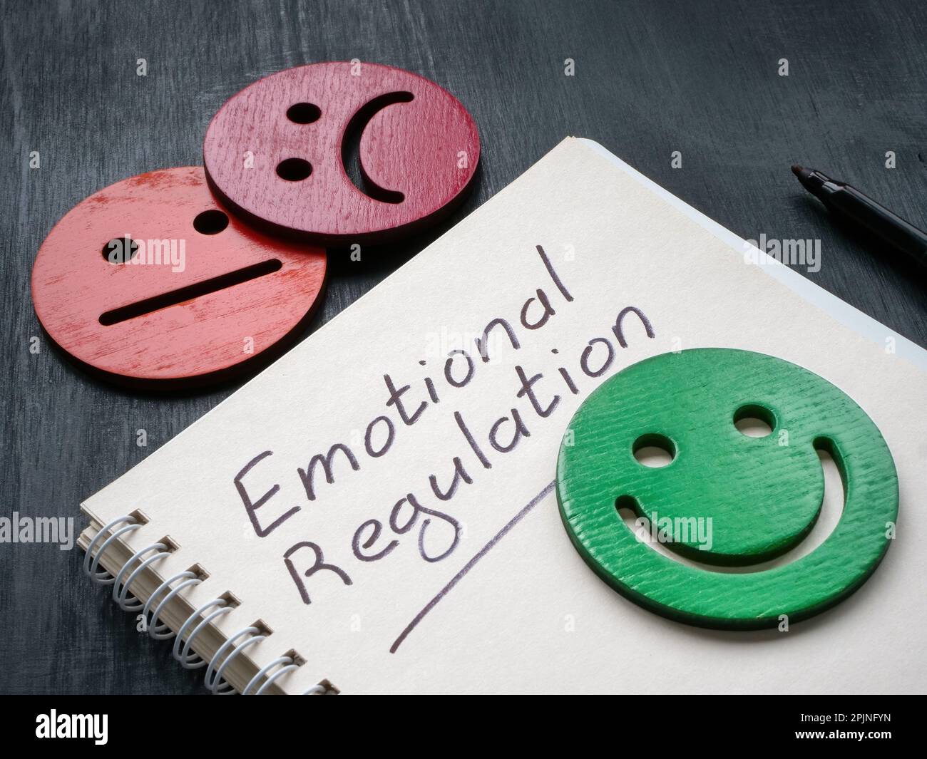 Notizblock mit Inschrift emotionale Regulation und Smiley. Stockfoto