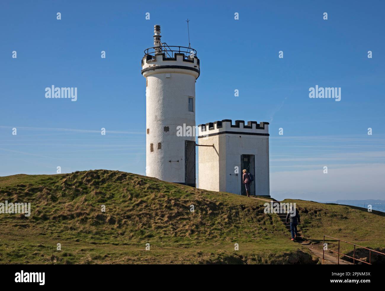 Fife, Schottland, Großbritannien. 3. April 2023 Sonnenschein und blauer Himmel mit herrlichen Ausblicken hätten jeden Besucher glauben lassen können, dass sie im Süden Frankreichs statt an der Küste von Fife wären. Obwohl es nach Minustemperaturen über Nacht und der Morgentemperatur bei 8 Grad Celsius und der Erwärmung auf etwas mehr als 10 Grad am Nachmittag vielleicht etwas kühler war als auf dem Kontinent. Abbildung: Ein Paar, das in Richtung Elie Ness Lighthouse klettert, das sich am East Neuk of Fife auf der Landzunge zwischen Inchkeith und der Isle of May befindet. Kredit: Archwhite/alamy Live News. Stockfoto