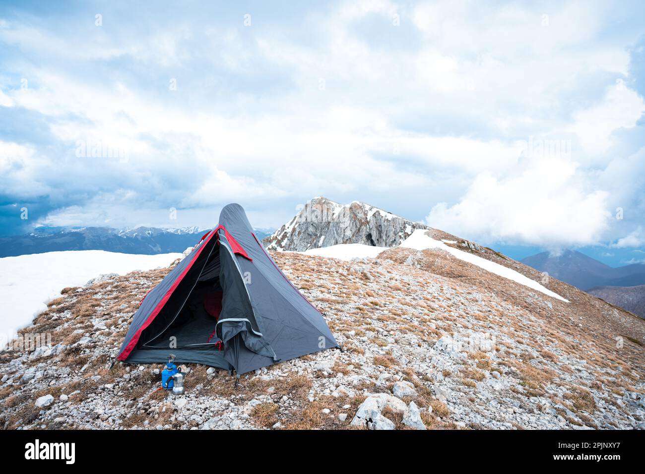 (Selektiver Fokus) atemberaubender Blick auf ein Campingzelt auf dem Gipfel des Monte Pratillo mit schneebedeckten Bergen in der Ferne. Stockfoto