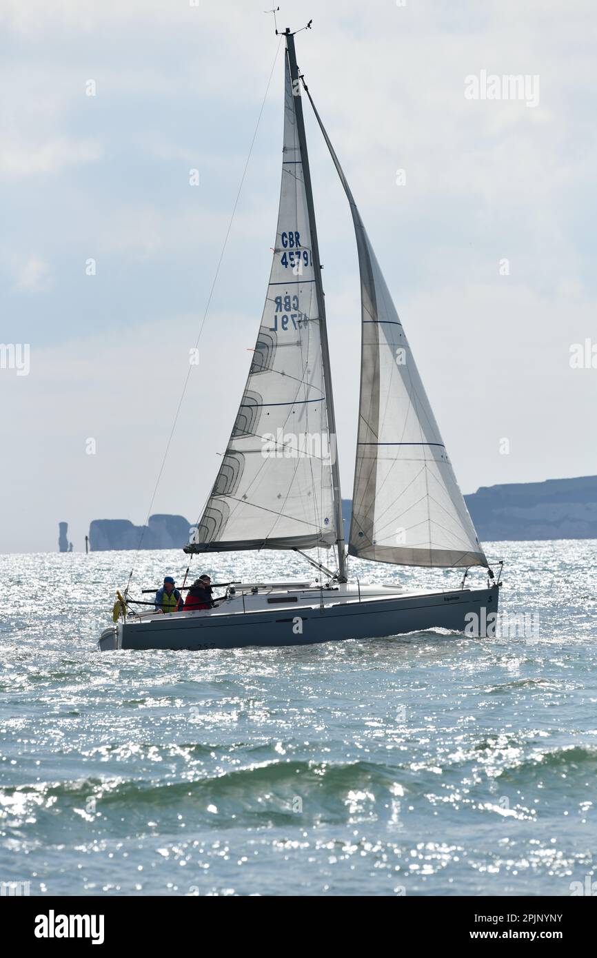 Yacht in Bournemouth Bay nähert sich Poole Harbour Eingang mit Studland und Old Harry Rocks im Hintergrund Stockfoto