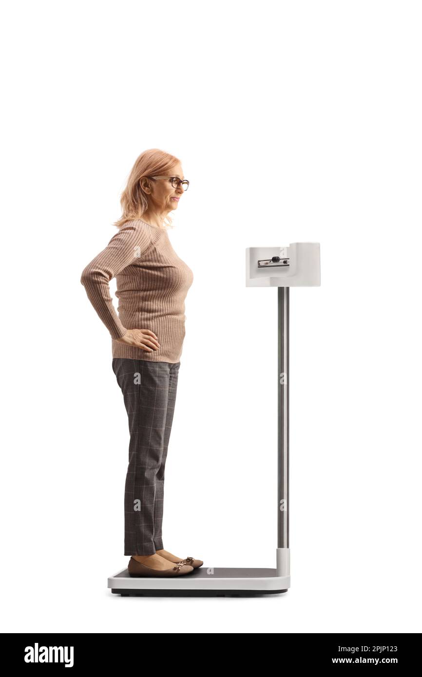 Profil mit voller Länge Aufnahme einer Frau, die ihr Gewicht auf einer professionellen medizinischen Skala auf weißem Hintergrund isoliert überprüft Stockfoto