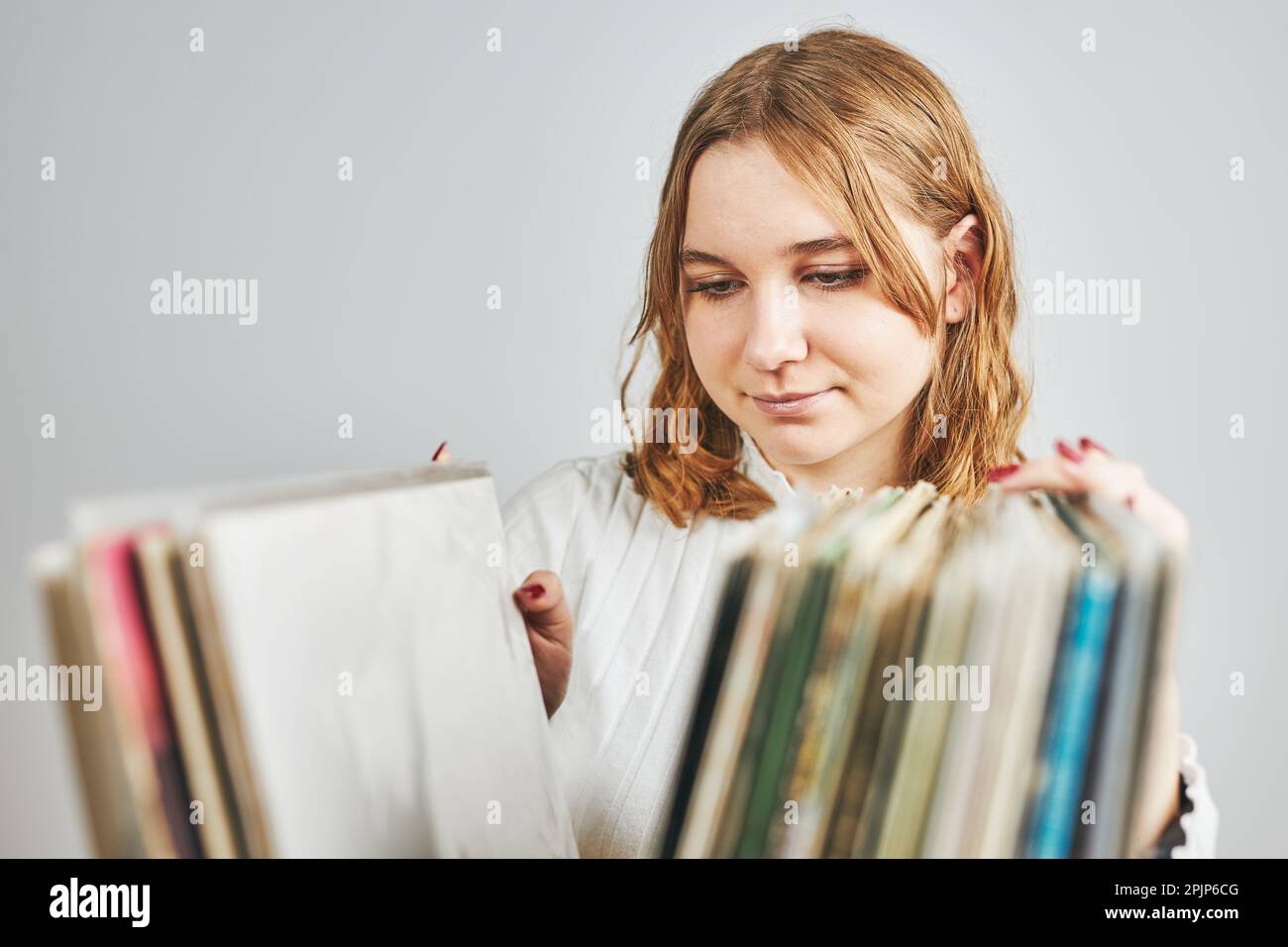 Vinyl-Schallplatten spielen. Musik von einem Vinyl-Plattenspieler hören. Retro- und Vintage-Musikstil. Junge Frau sucht analoges LP-Album in sta Stockfoto