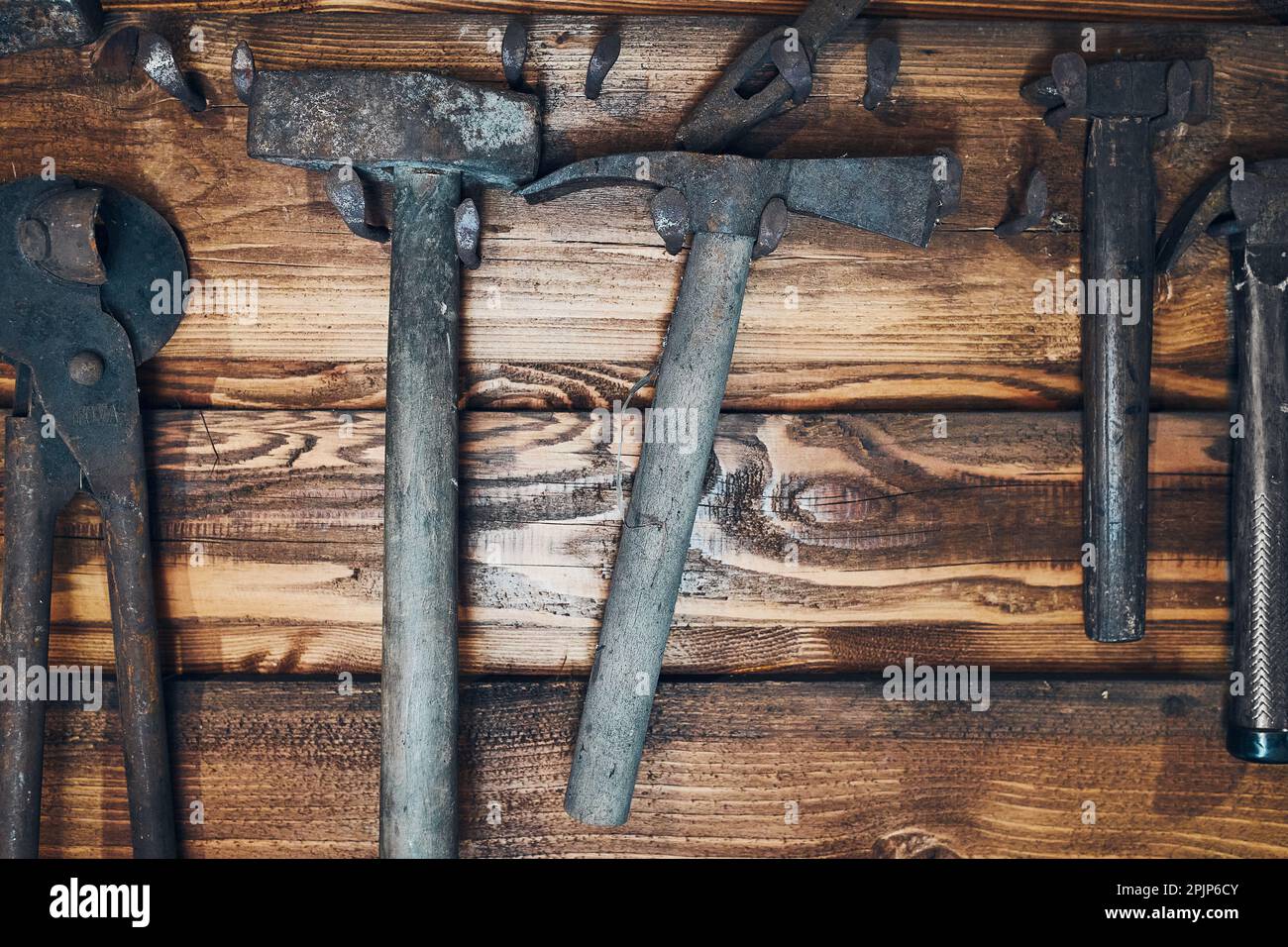 Alte rostige Schmiede-Werkzeuge hing an der Holzwand Stockfoto