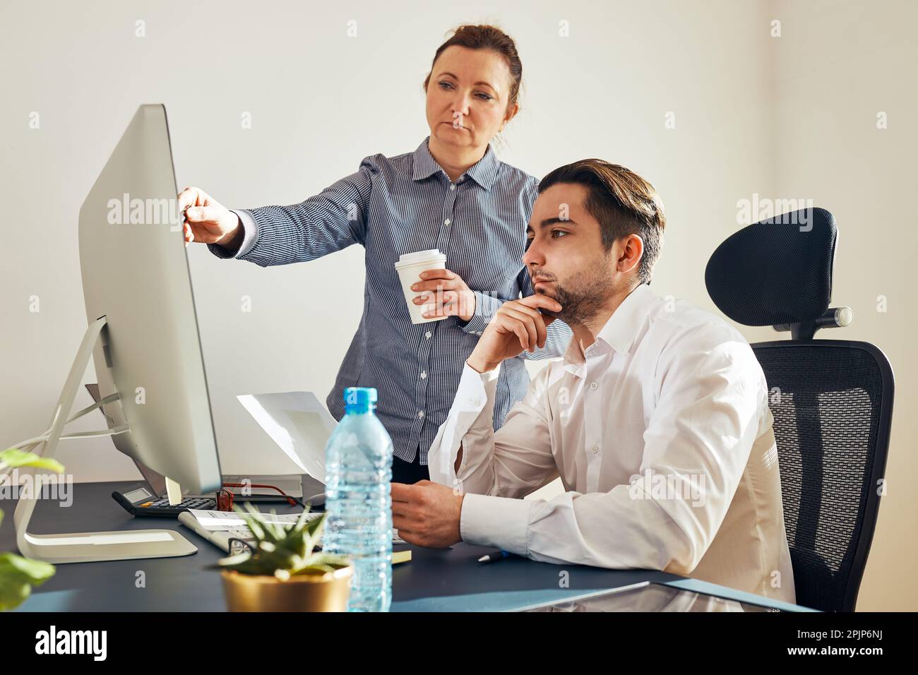 Zwei Geschäftsleute diskutieren Finanzdaten am Computer. Geschäftsfrau, die mit einem männlichen Kollegen im Büro zusammenarbeitet. Menschen Unternehmer arbeiten mit char Stockfoto