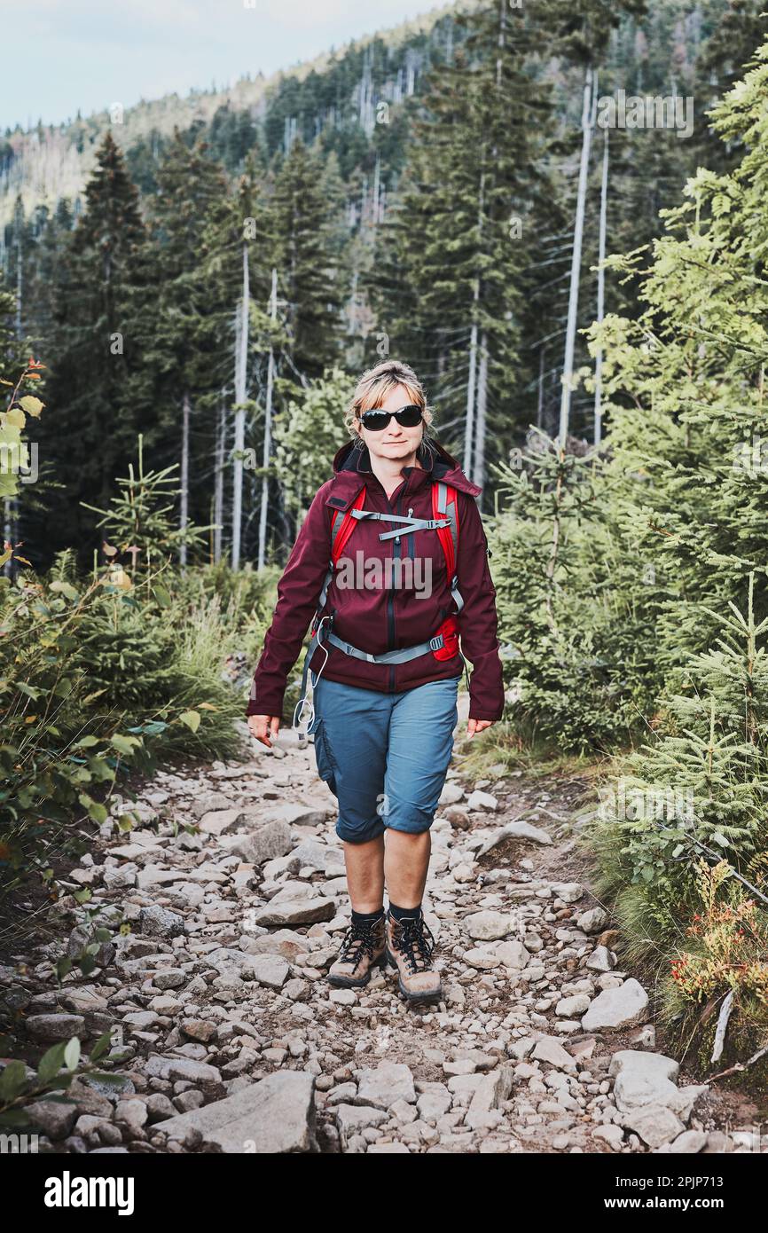 Frau mit Rucksack Wandern in den Bergen, verbringen Sommerurlaub in der Nähe der Natur. Frau, die auf dem Weg zwischen Büschen und Bäumen geht Stockfoto