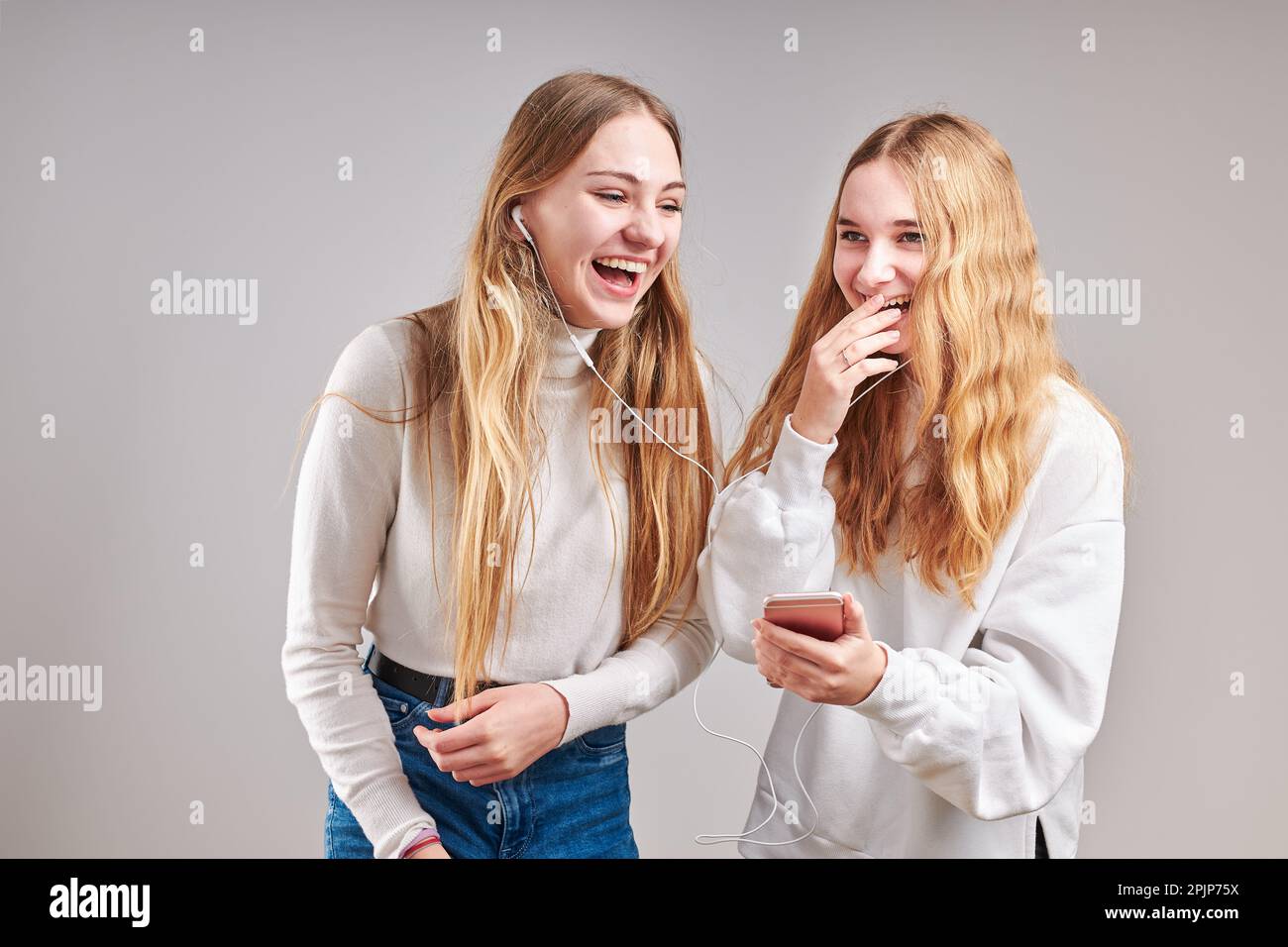 Junge Frauen Mädchen hören zusammen Musik Streaming-Inhalte Spaß beim Ansehen von Videos genießen Video-Chat mit Freunden reden machen Gesten fac Stockfoto