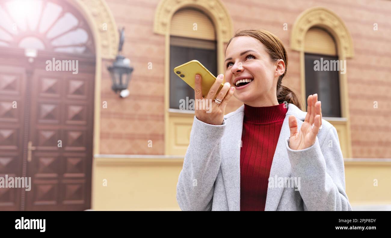Brünette Frau nimmt Sprachnachricht mit ihrem Smartphone auf. Stockfoto